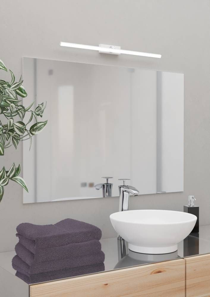 Luminaire blanc et chromé installé au-dessus d'un miroir dans une salle de bain.
