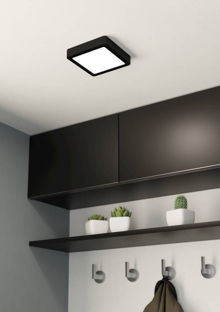 Plafonnier carré noir allumé au plafond dans une entrée avec meubles et porte-manteaux.