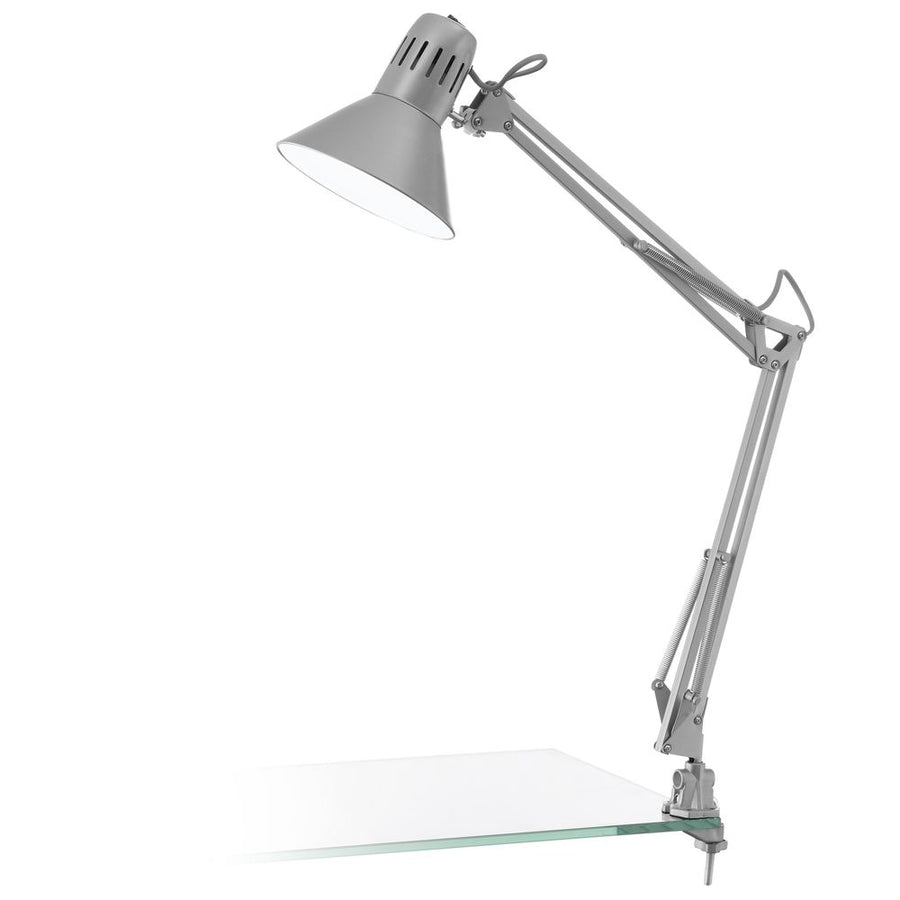 Lampe d'architecte argentée articulée, pince visible sur support en verre, fond blanc