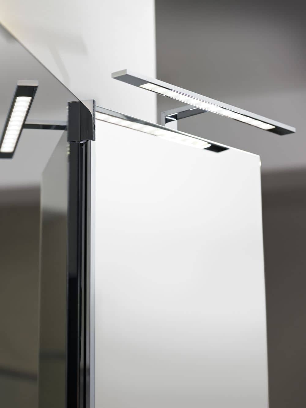 Mise en ambiance : applique allumée au-dessus d'un miroir de salle de bains