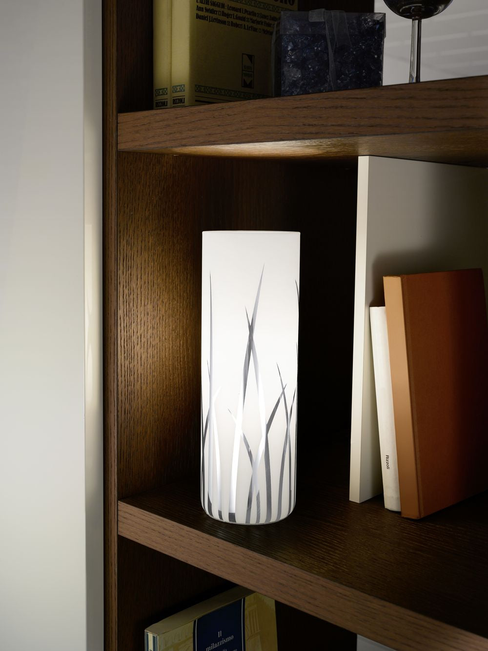 Lampe allumée posée sur une étagère en bois, ambiance chaleureuse de bibliothèque