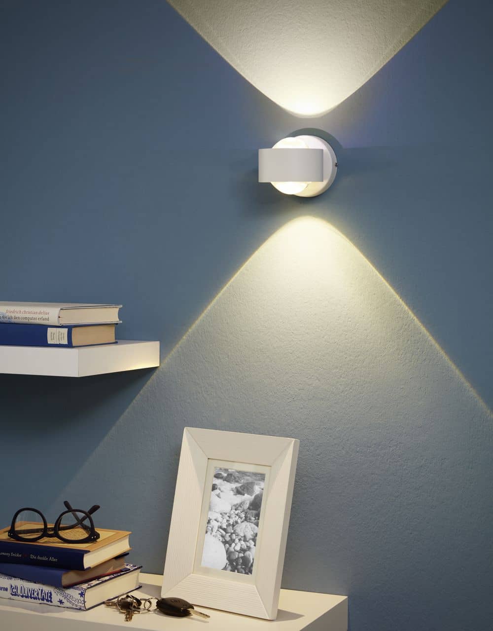 Mise en ambiance sur mur bleu, applique allumée diffusant lumière vers le haut et le bas