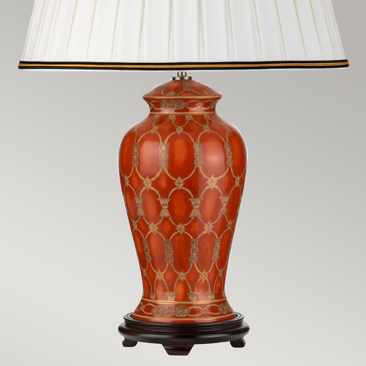 Gros plan sur la base en céramique rouge avec décor géométrique doré et socle noir.