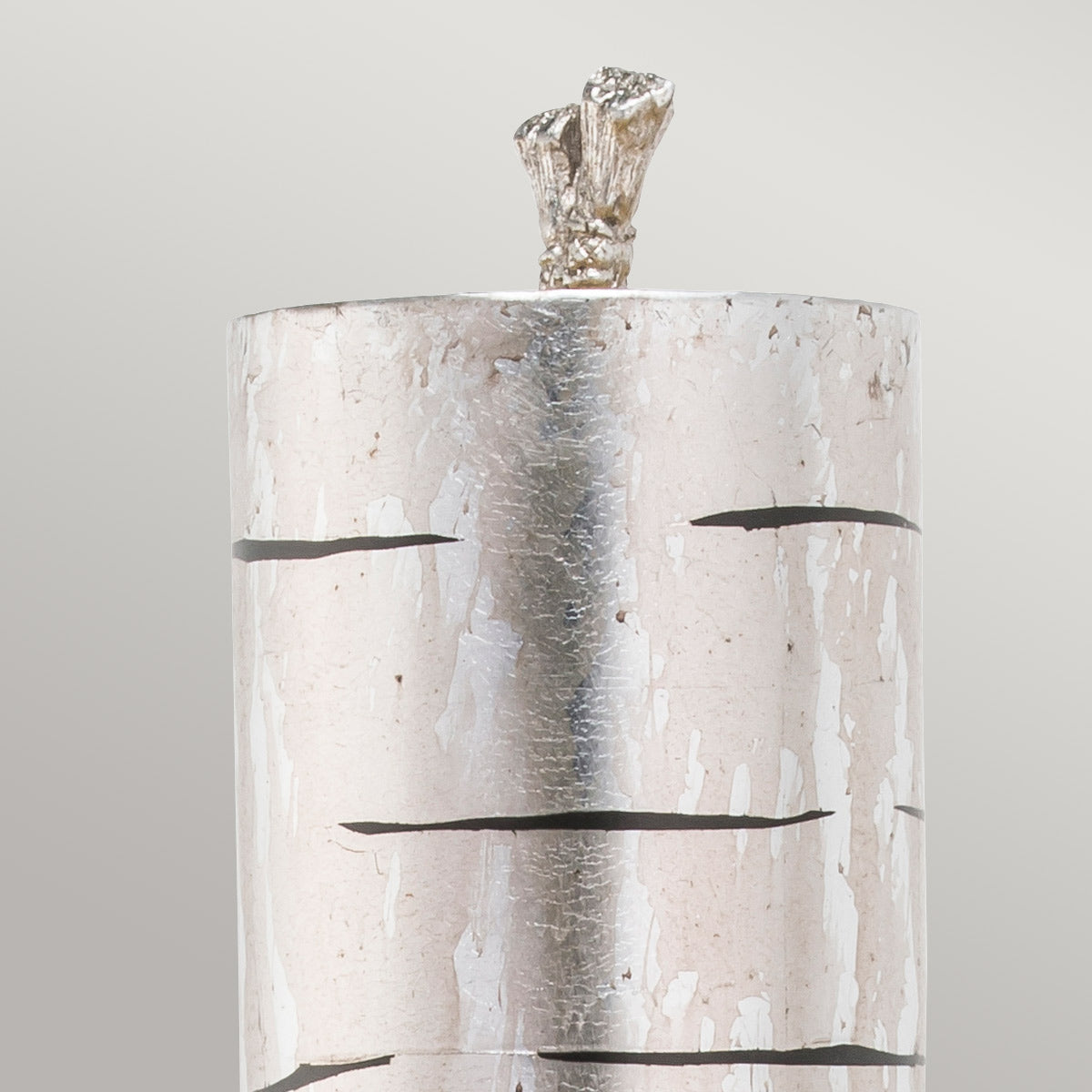 Détail du sommet de l'abat-jour cylindrique argenté et de son ornement sommital.