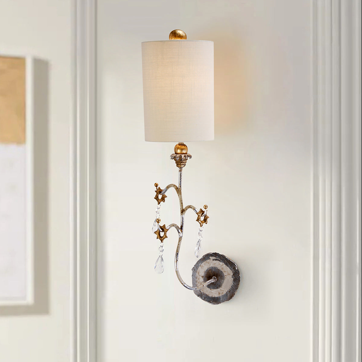 Mise en ambiance de l'applique allumée sur un mur blanc mouluré