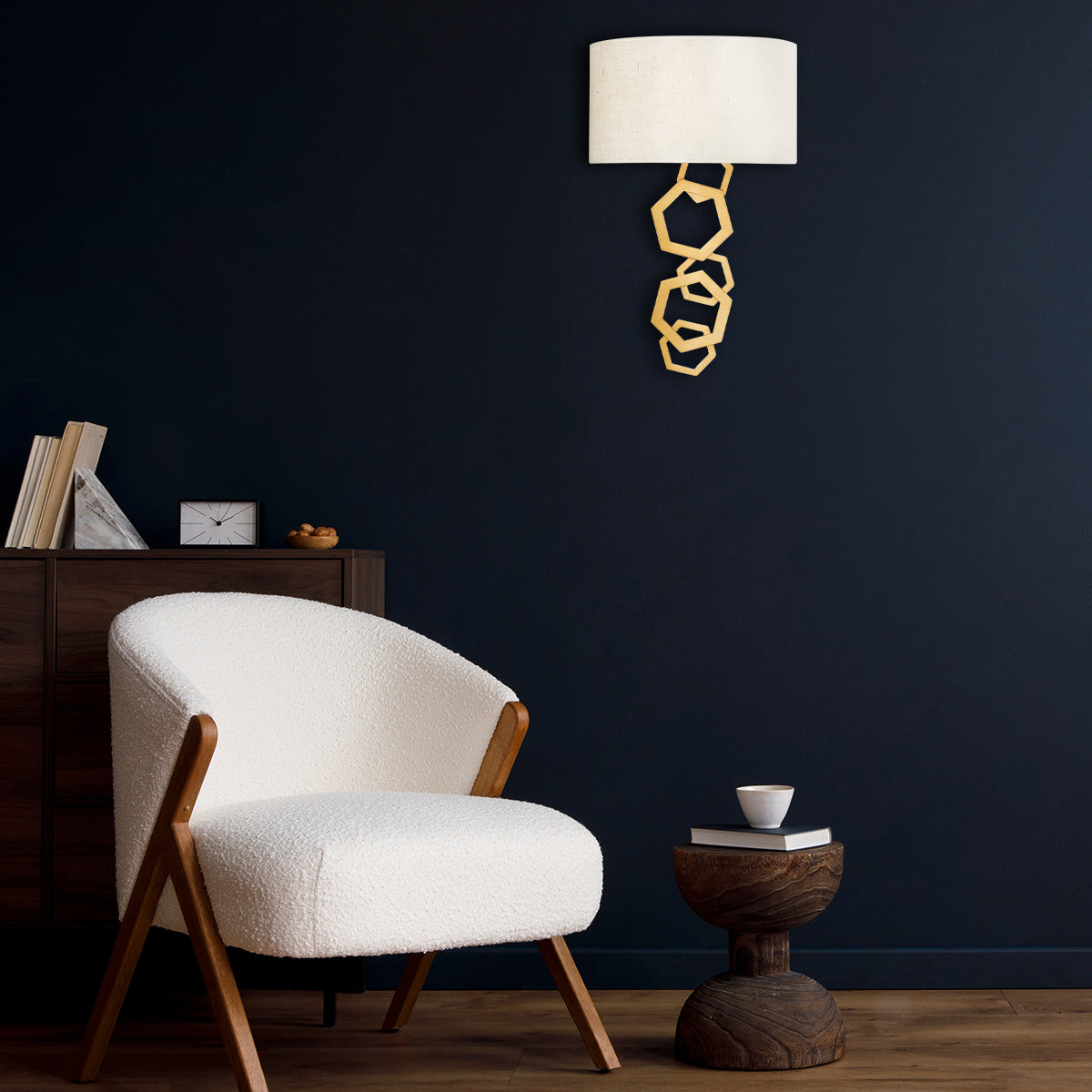 Mise en ambiance de l'applique dorée sur un mur bleu nuit près d'un fauteuil