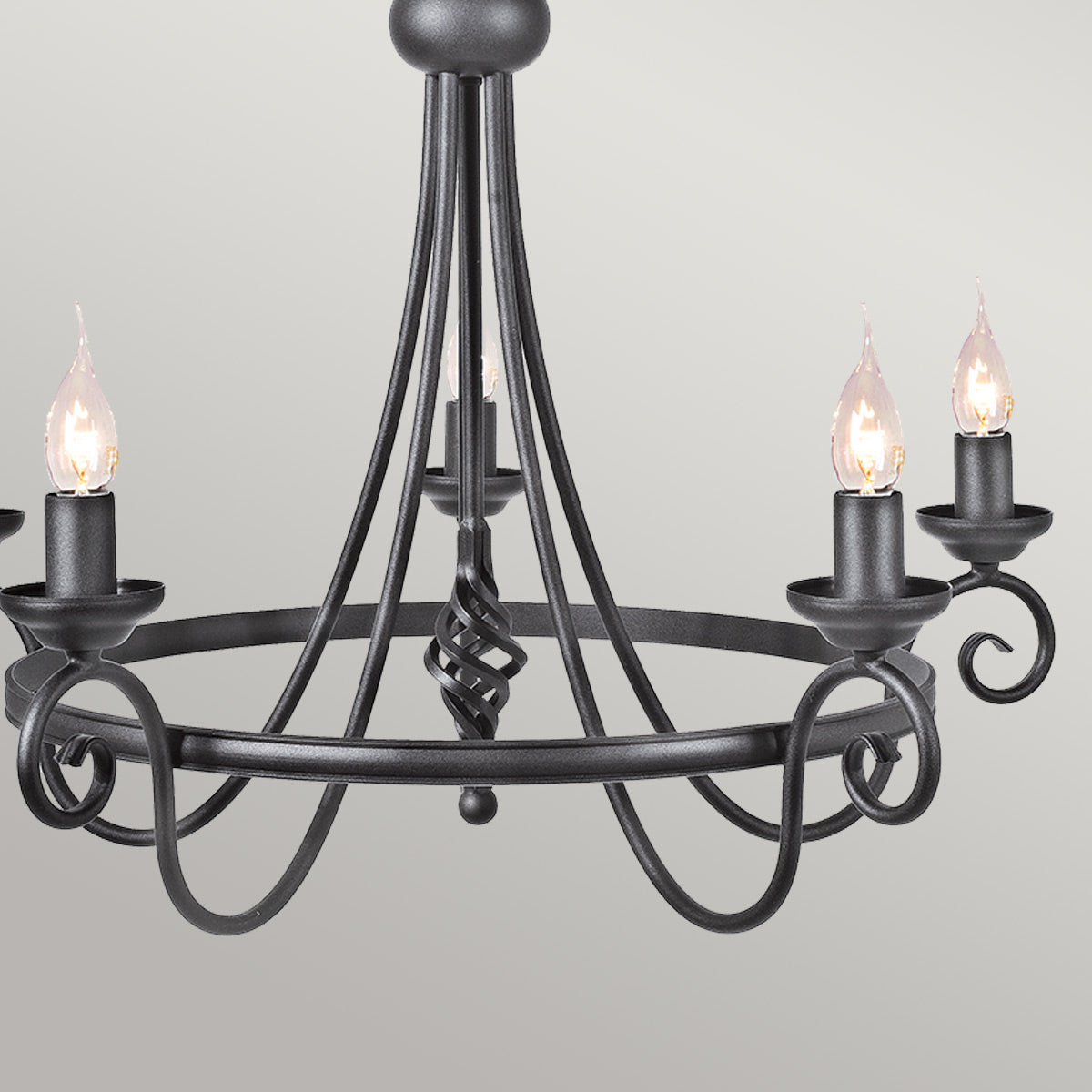 Gros plan des bras courbes, volutes et bougies allumées du lustre