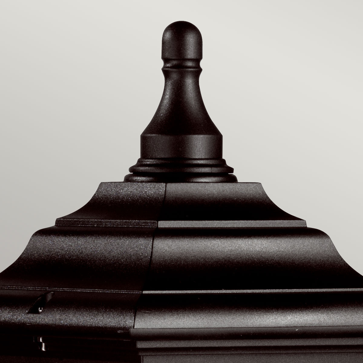 Gros plan sur le sommet mouluré et la pointe décorative noire du lampadaire