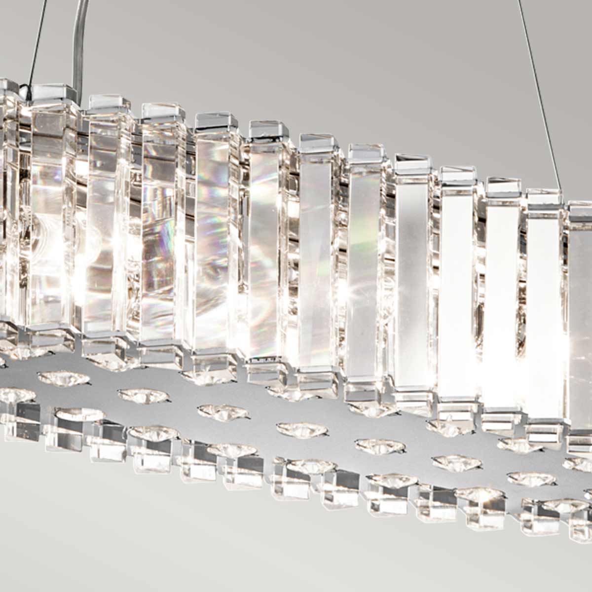 Détail des prismes de cristal et de la base chromée ajourée, reflets irisés.