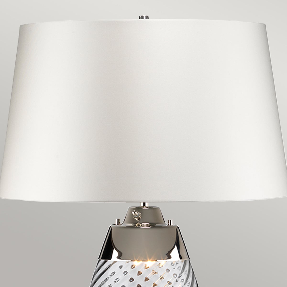 Gros plan sur l'abat-jour blanc et la bague chromée de la lampe