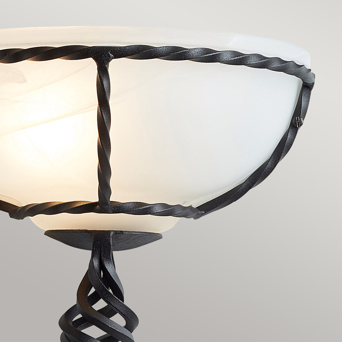 Détail du cerclage en fer torsadé noir maintenant la vasque de verre blanc