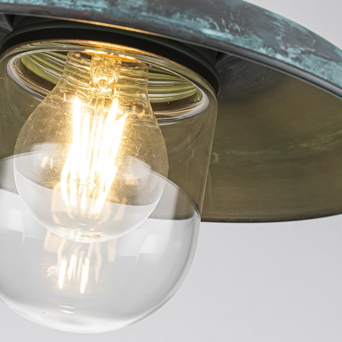 Gros plan sur l'ampoule dorée et le globe de verre sous l'abat-jour patiné
