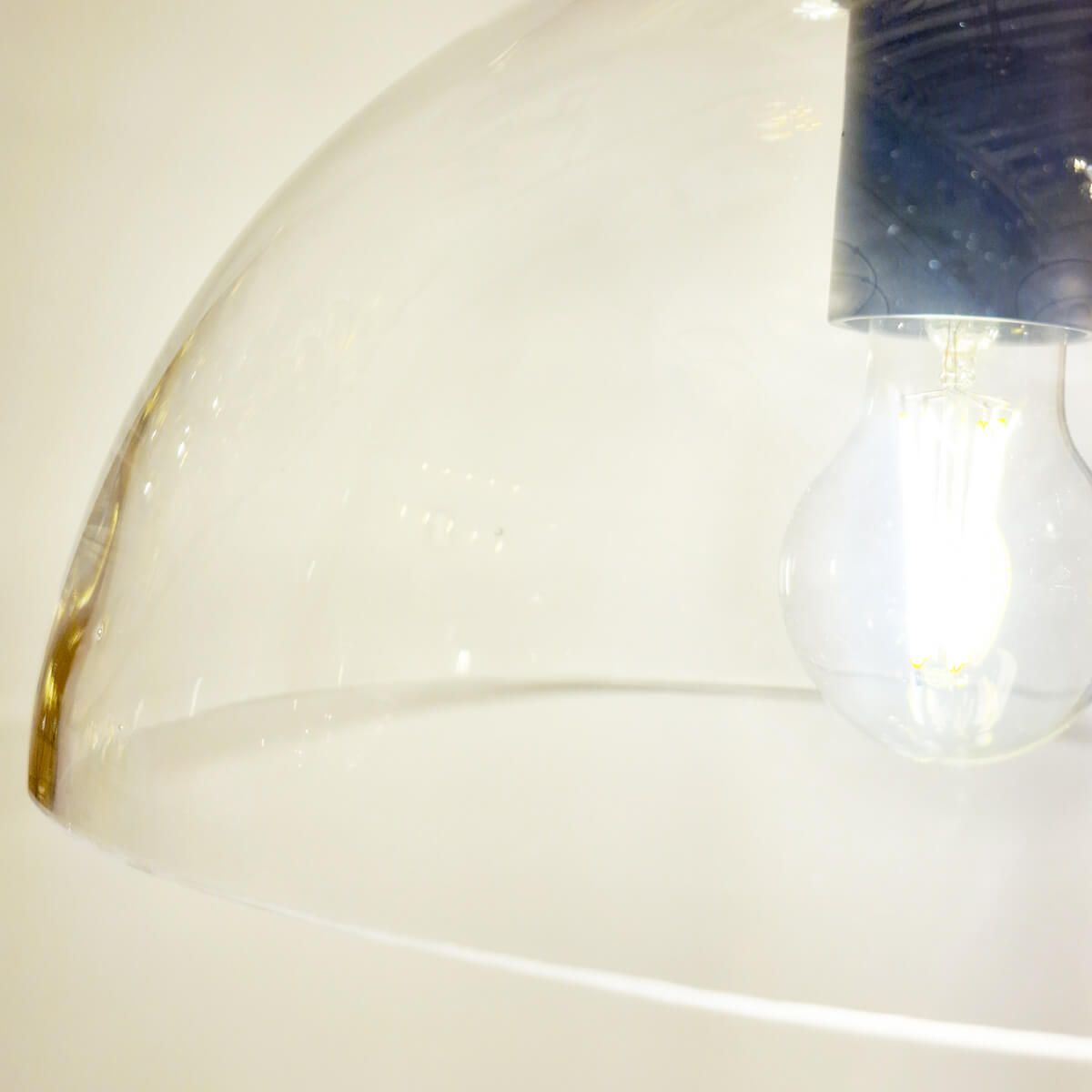 Gros plan du globe en verre transparent et de l'ampoule allumée à l'intérieur.