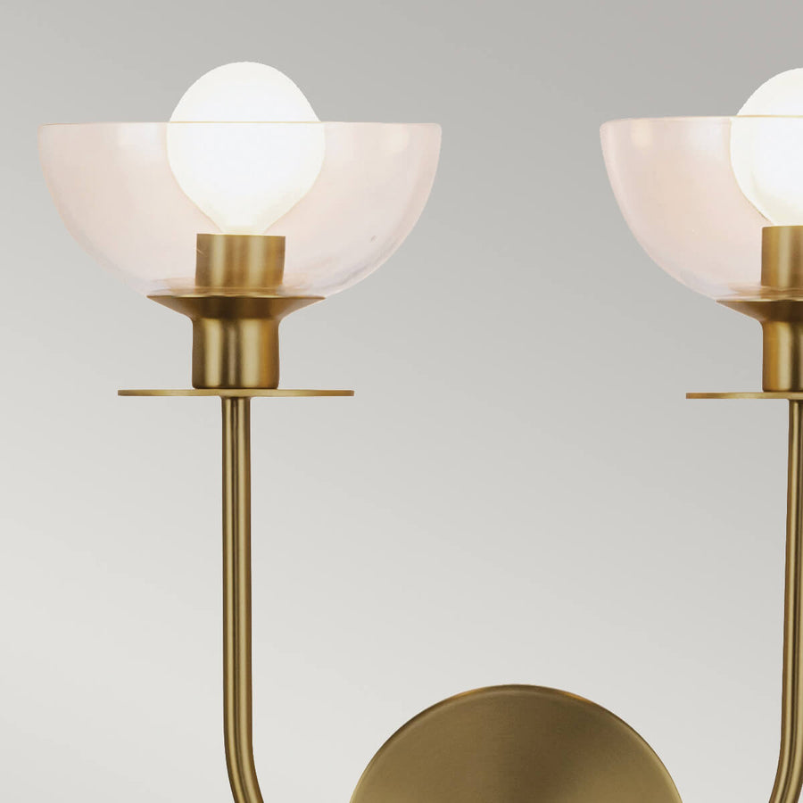 Détail d'une lumière allumée sous une coupelle en verre transparent et douille dorée