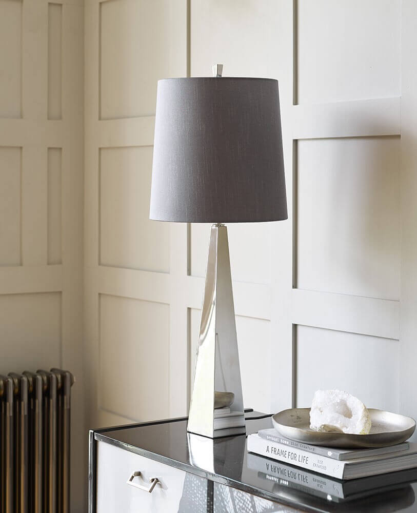 Mise en ambiance sur une commode en miroir devant une cloison à panneaux blancs