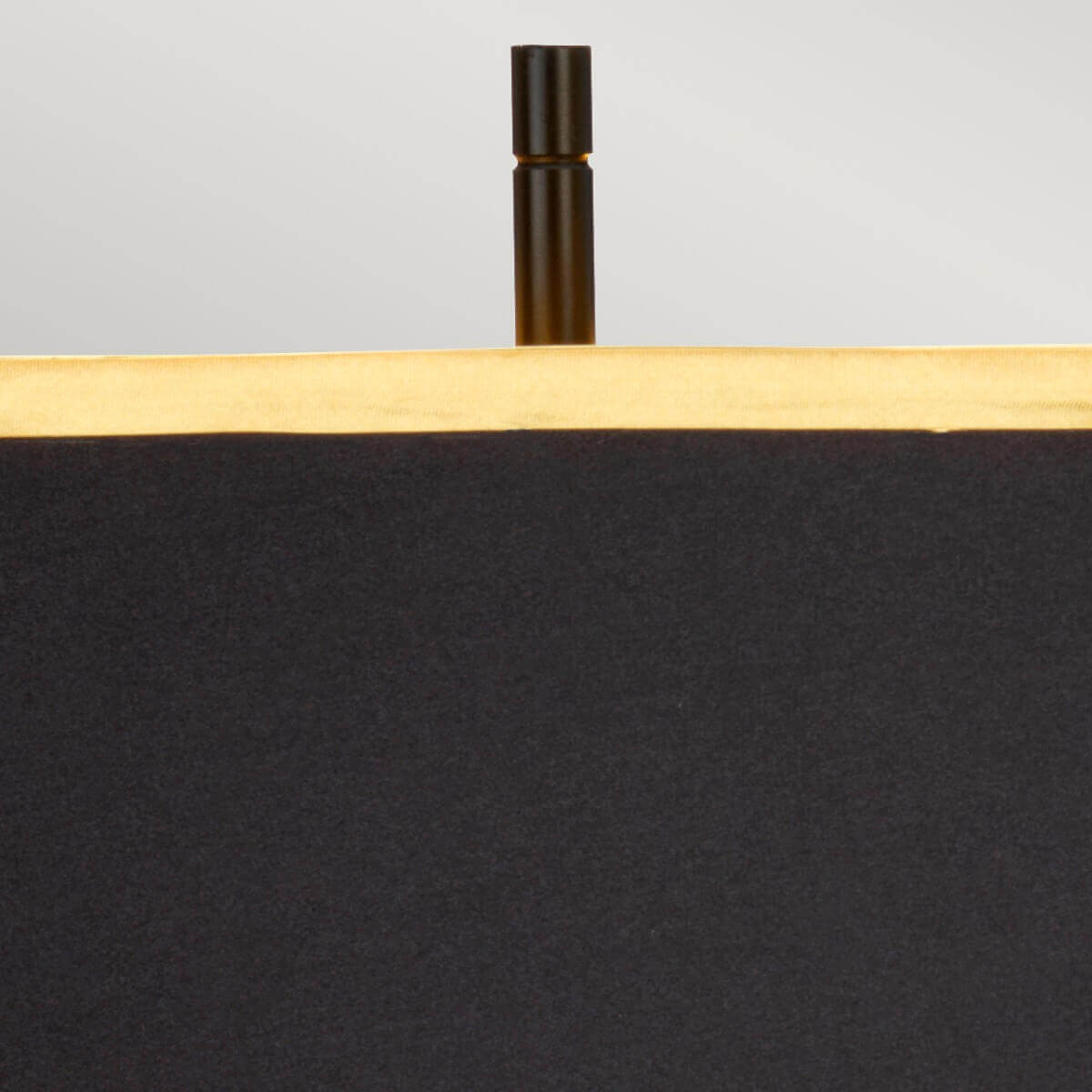 Détail du sommet avec finition noire cylindrique dépassant au-dessus de l’abat-jour doré.