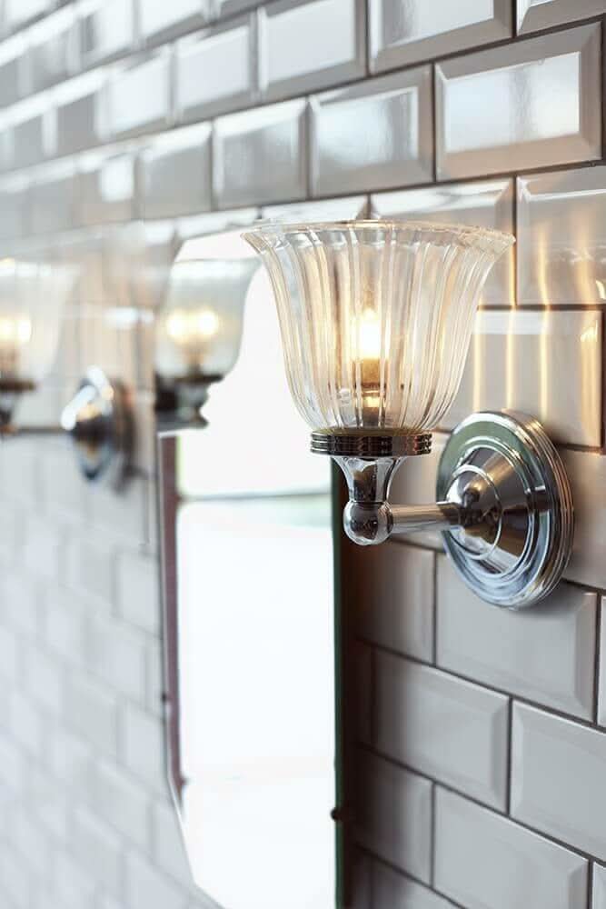 Vue rapprochée de l'applique allumée devant un mur de faïence blanche et un miroir