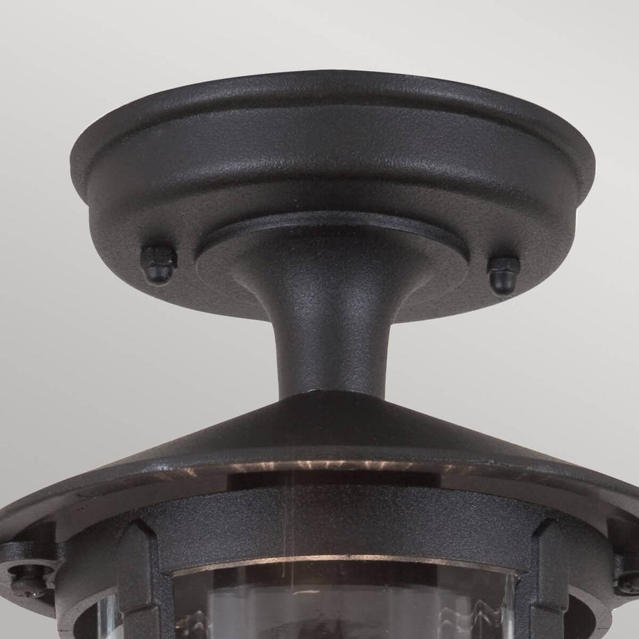 Détail de la fixation au plafond, rosace ronde noire et vis apparentes