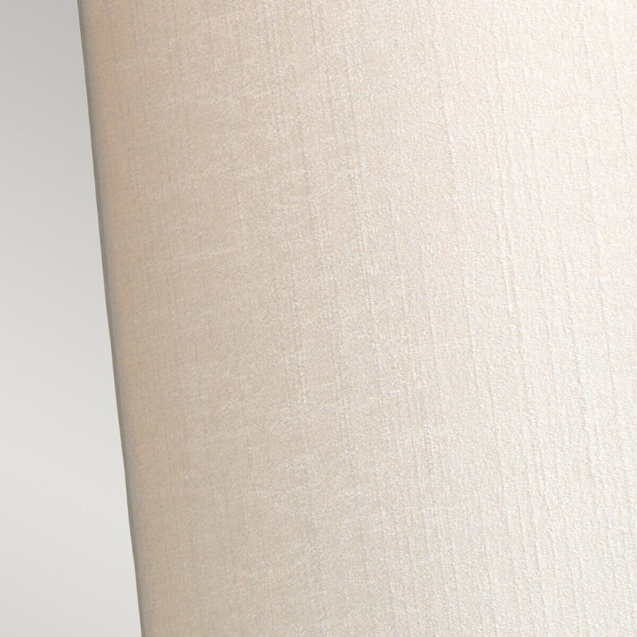 Détail rapproché du tissu texturé beige et de la courbure de l'abat-jour.