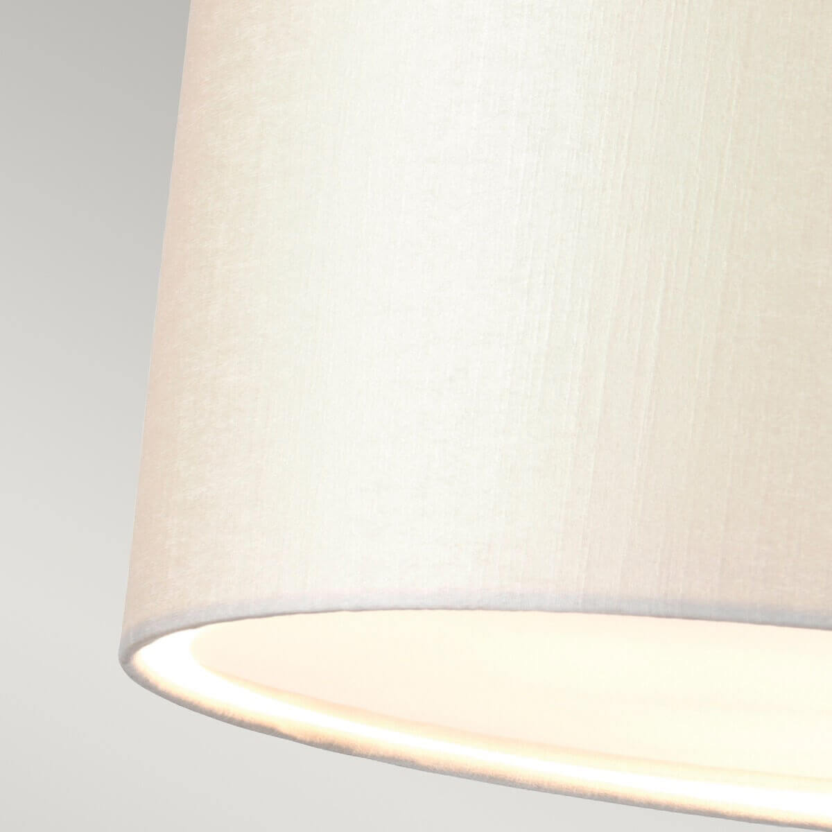 Détail gros plan de la texture tissu crème et bord inférieur éclairé.
