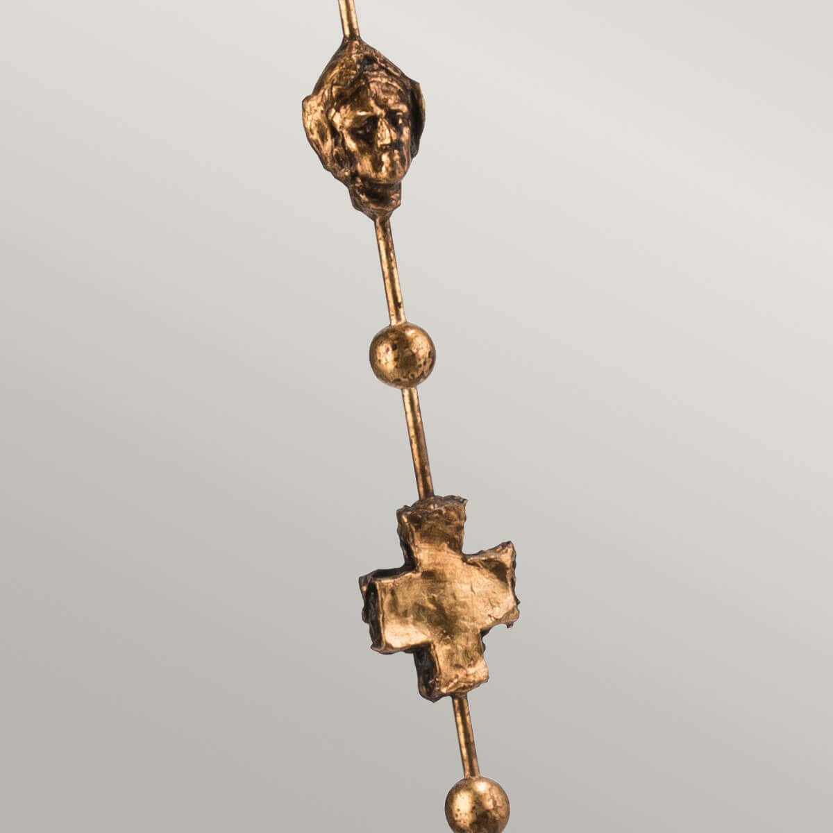 Détail du fût doré avec visage sculpté et croix en relief entre deux billes.