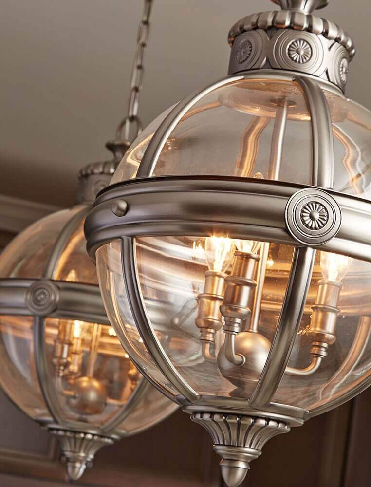 Deux luminaires suspendus allumés dans une pièce, ampoules chaudes visibles à travers le verre