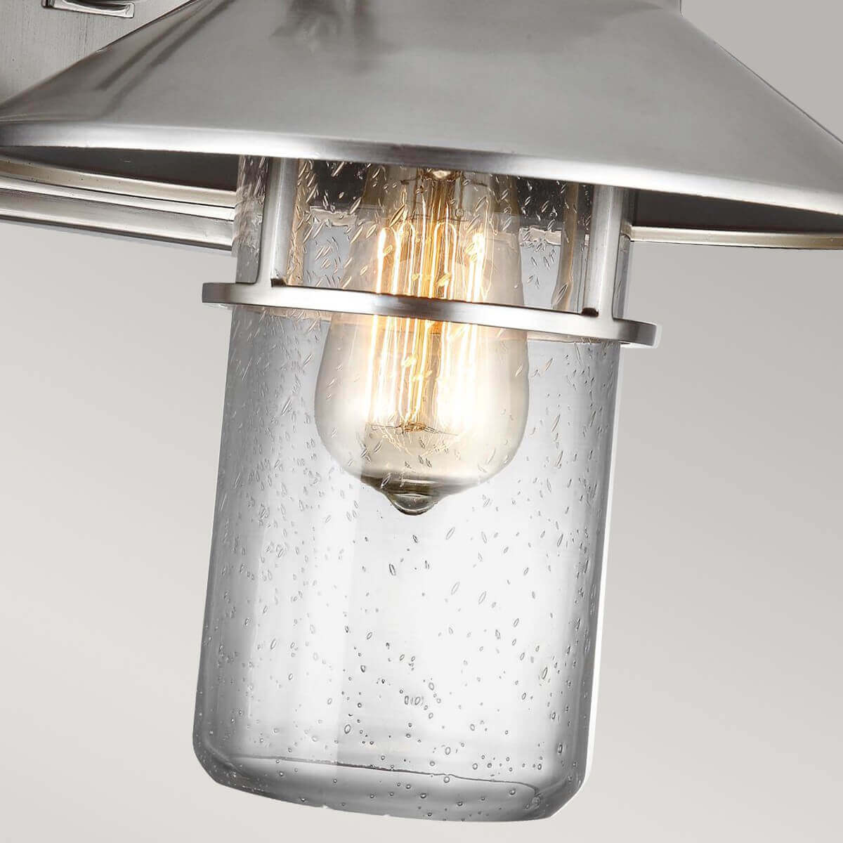 Détail du cylindre en verre moucheté et de l'ampoule à filament allumée.