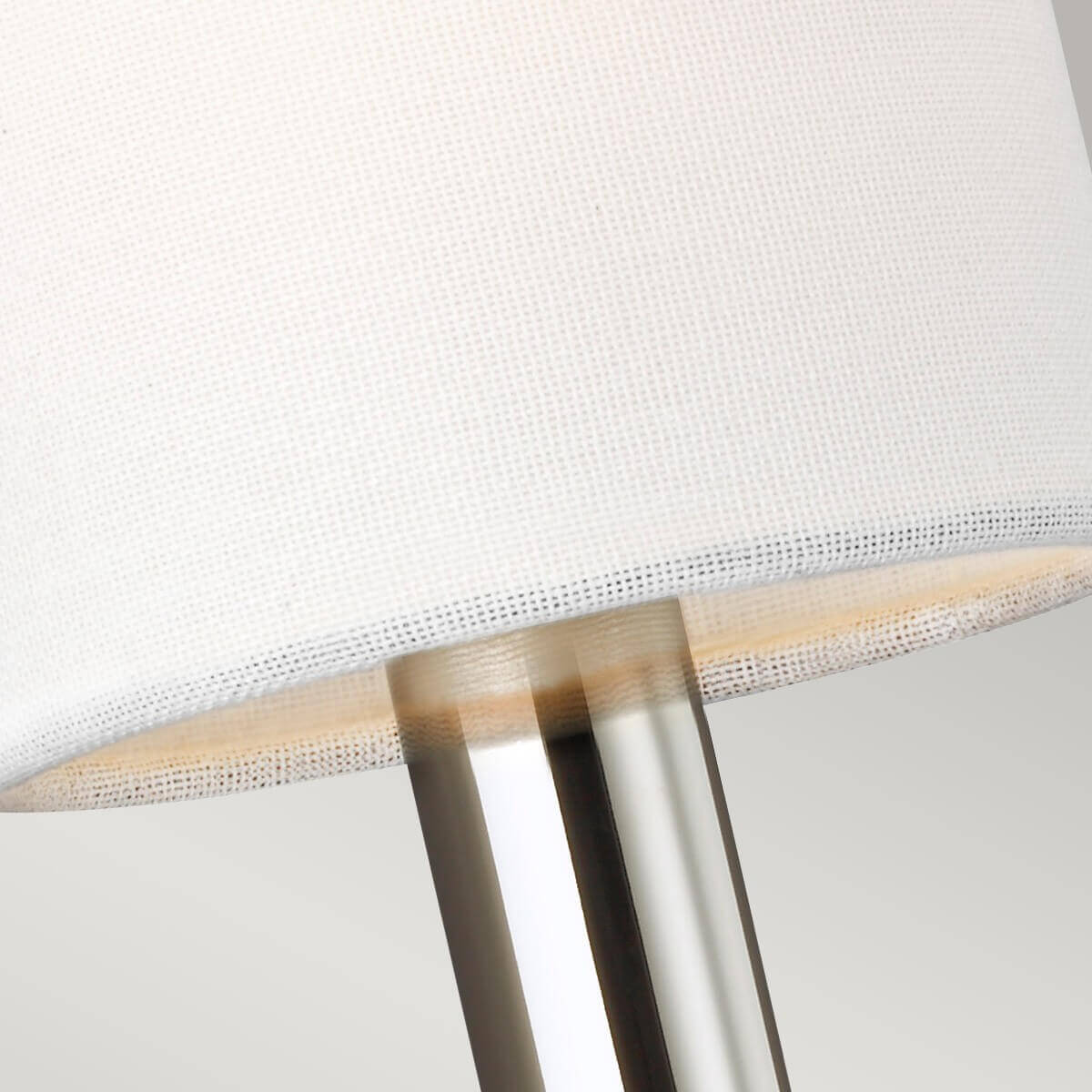 Détail rapproché du tissu blanc de l'abat-jour et de la tige métallique.