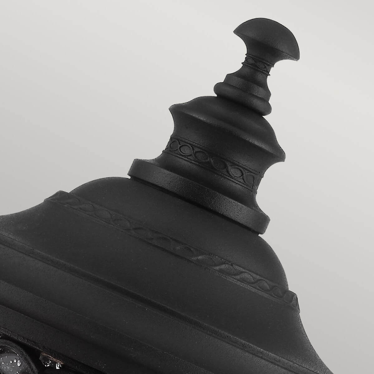 Gros plan sur le sommet mouluré et le chapeau noir du lampadaire