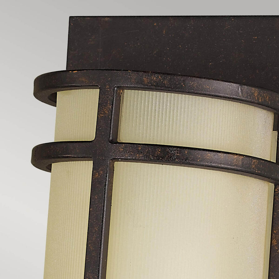 Gros plan sur le haut du luminaire montrant la croix métallique et la patine bronze