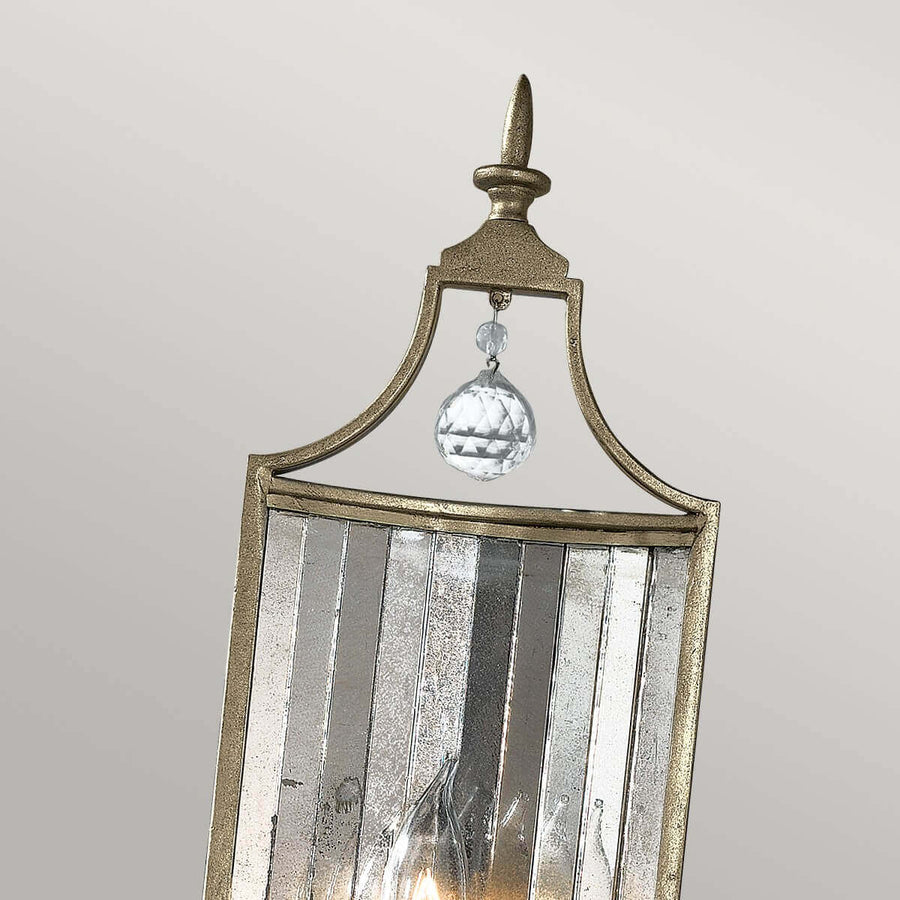 Détail du sommet doré avec pointe décorative et boule de cristal suspendue.