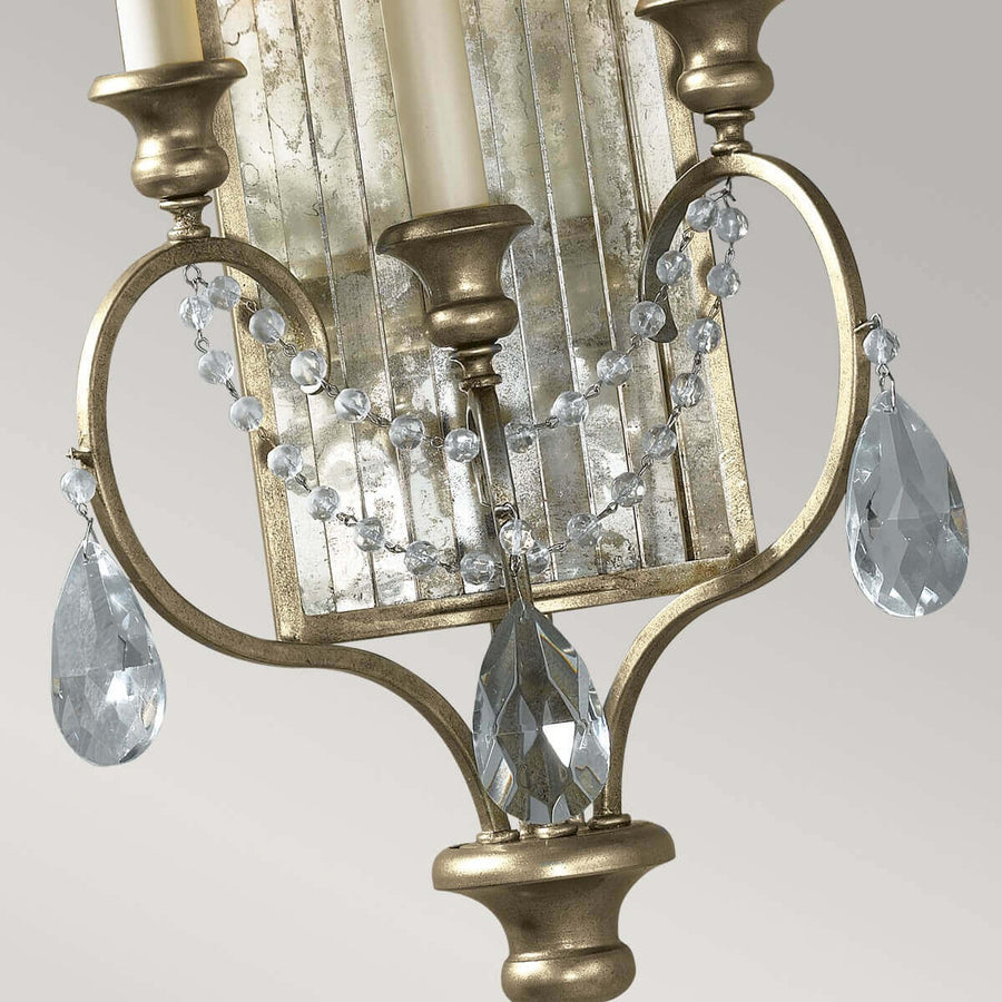 Détail des bras courbés dorés, chaînettes de perles et pampilles en cristal taillé