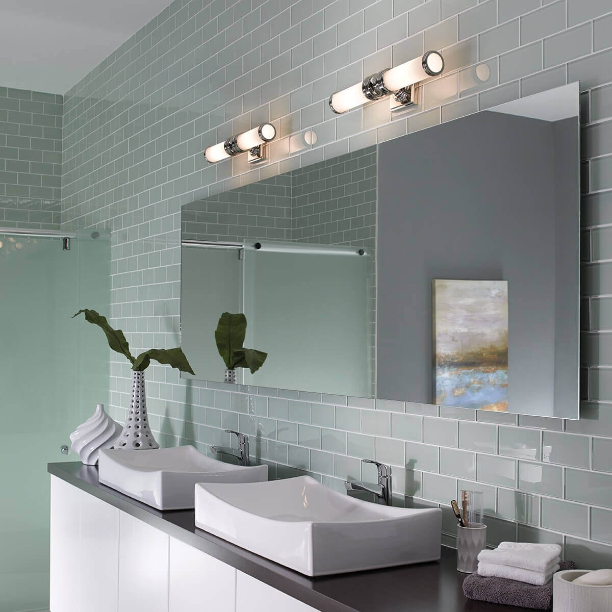 Mise en ambiance de deux appliques murales chromées éclairant un miroir de salle de bain.