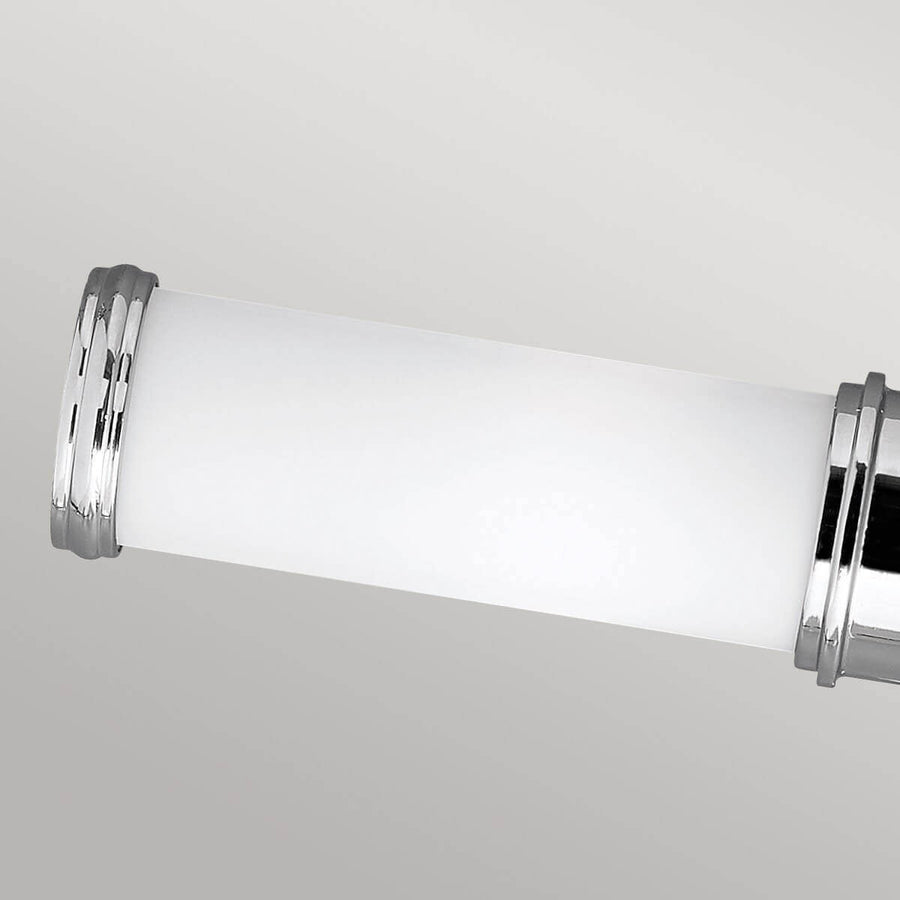 Gros plan sur un diffuseur cylindrique en verre blanc et son embout chromé.