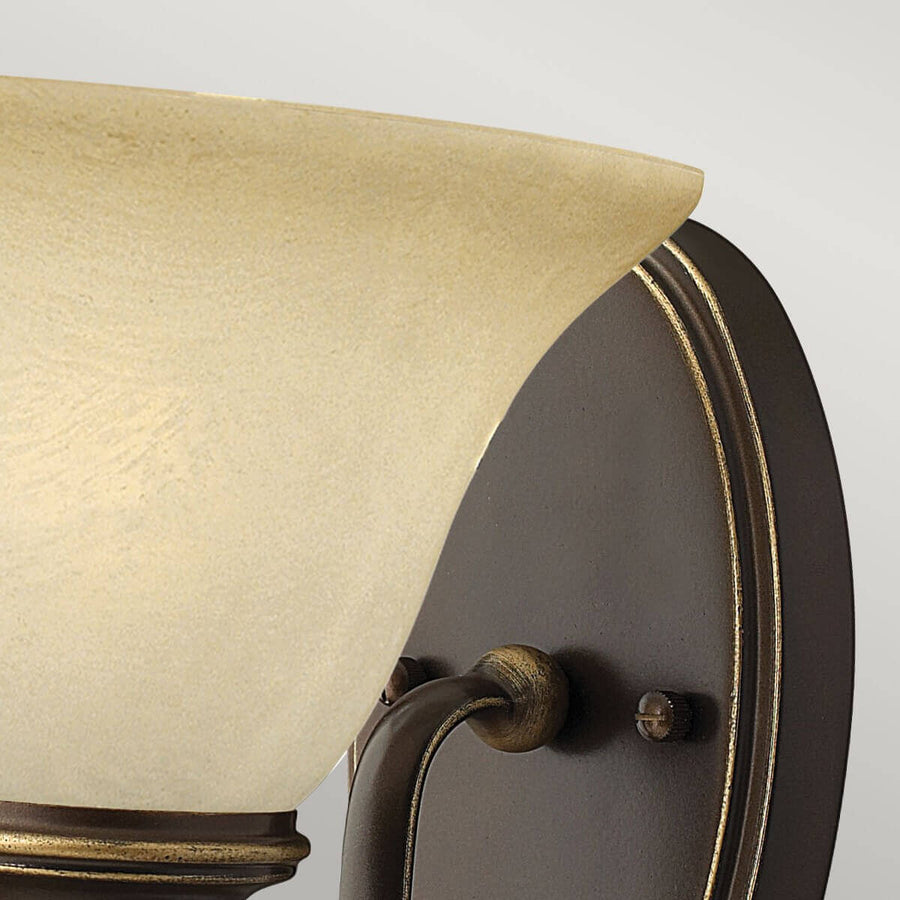 Détail de la fixation murale ovale et du bras recourbé en métal bronze