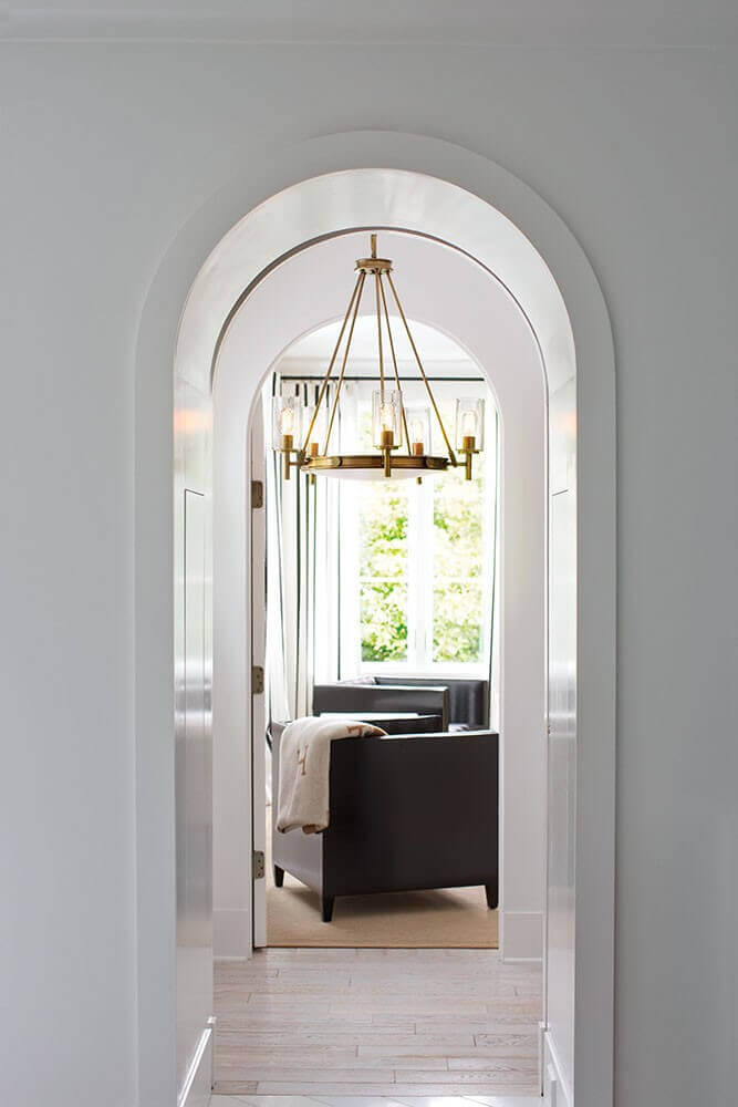 Mise en ambiance du lustre suspendu, aperçu à travers une arche dans un intérieur clair