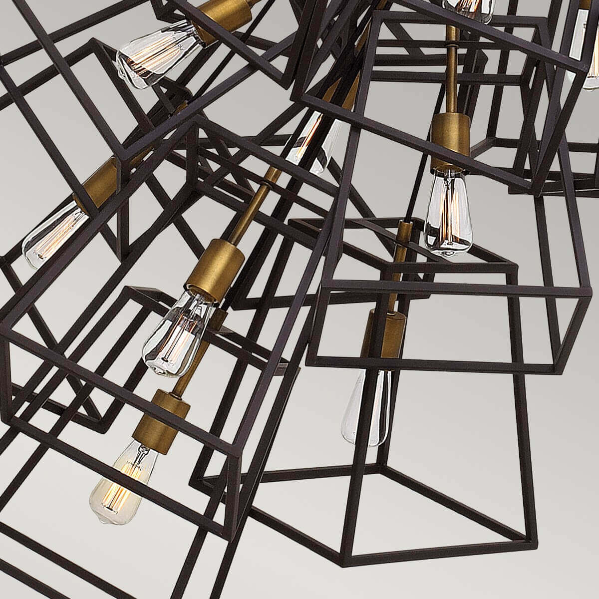 Gros plan sur les cages métalliques noires et les douilles bronze soutenant les ampoules Edison transparentes.