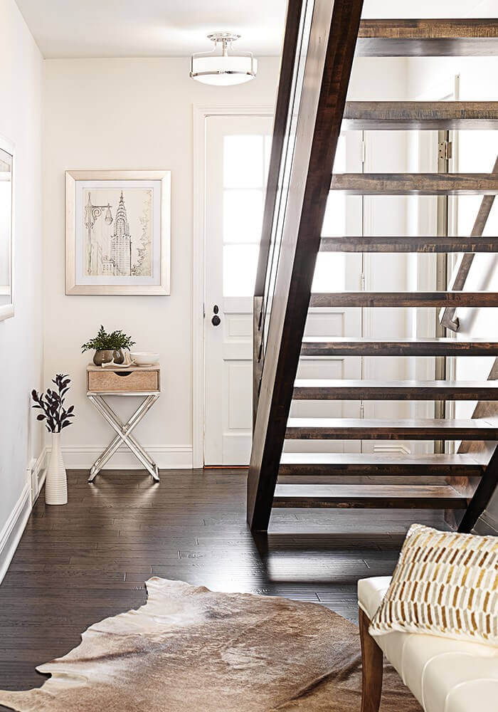 Mise en ambiance du plafonnier chromé installé au plafond dans une entrée avec escalier en bois.