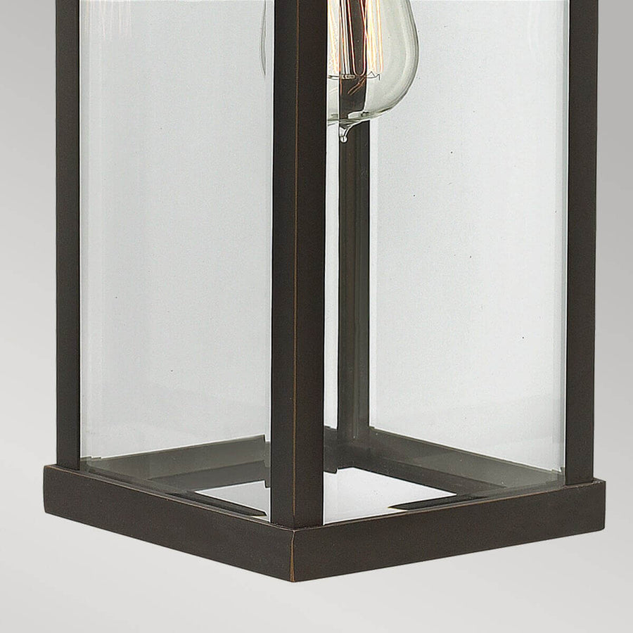 Détail de la base carrée et des panneaux de verre transparent du luminaire.
