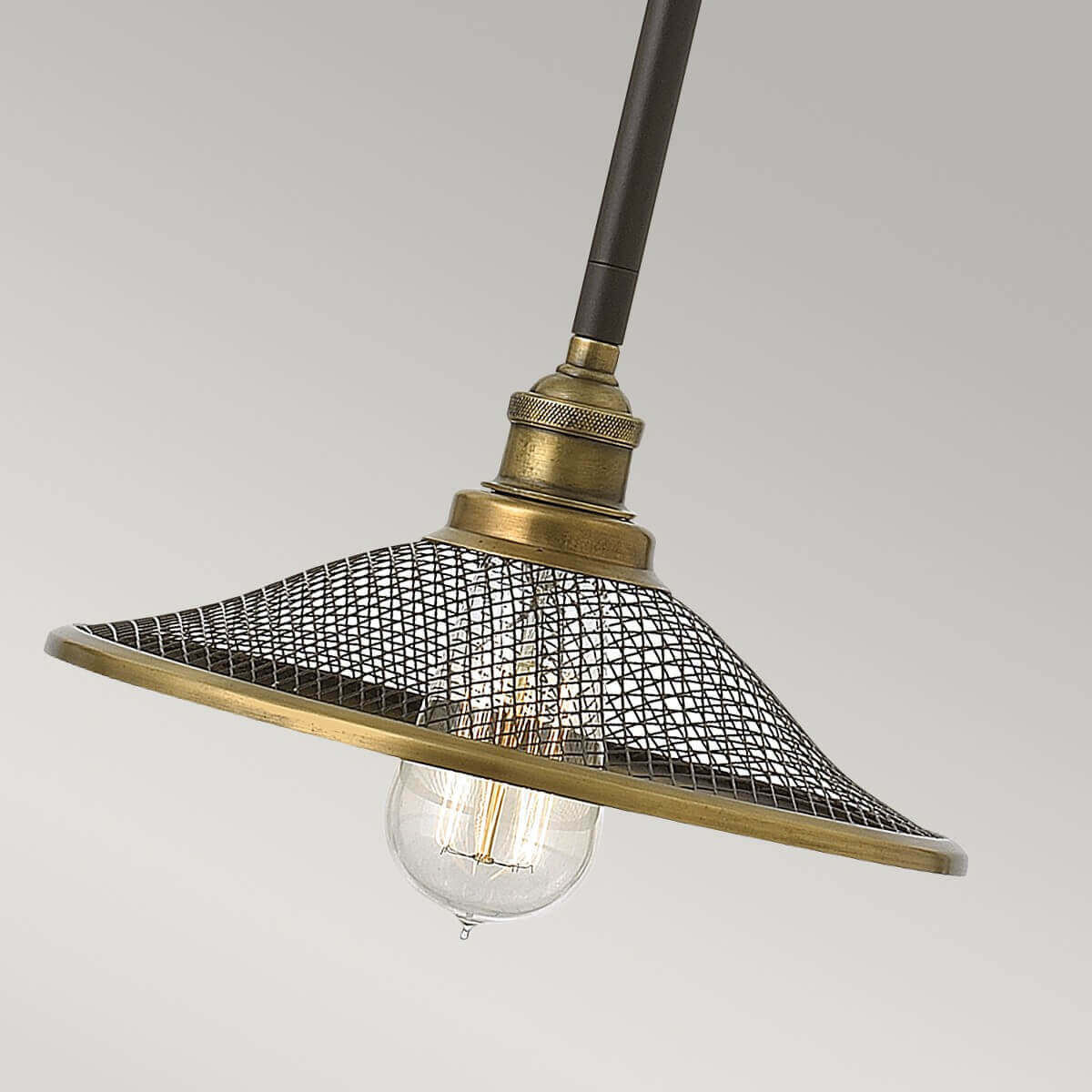 Gros plan sur l'abat-jour en maille métallique bronze et l'ampoule apparente