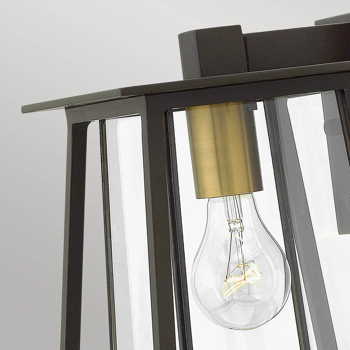 Détail du sommet du luminaire avec douille laiton et ampoule à filament.