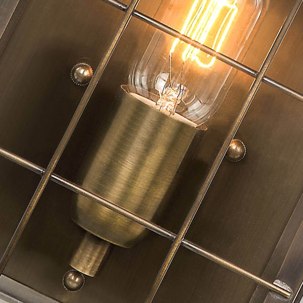 Détail du culot en laiton brossé et croisillons de la grille, ampoule allumée