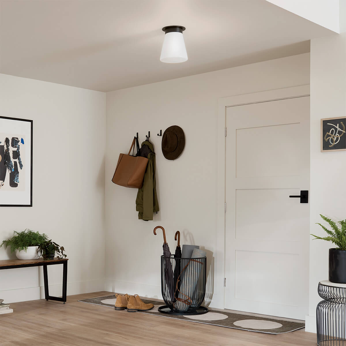 Mise en ambiance dans une entrée blanche avec patères, panier à parapluies