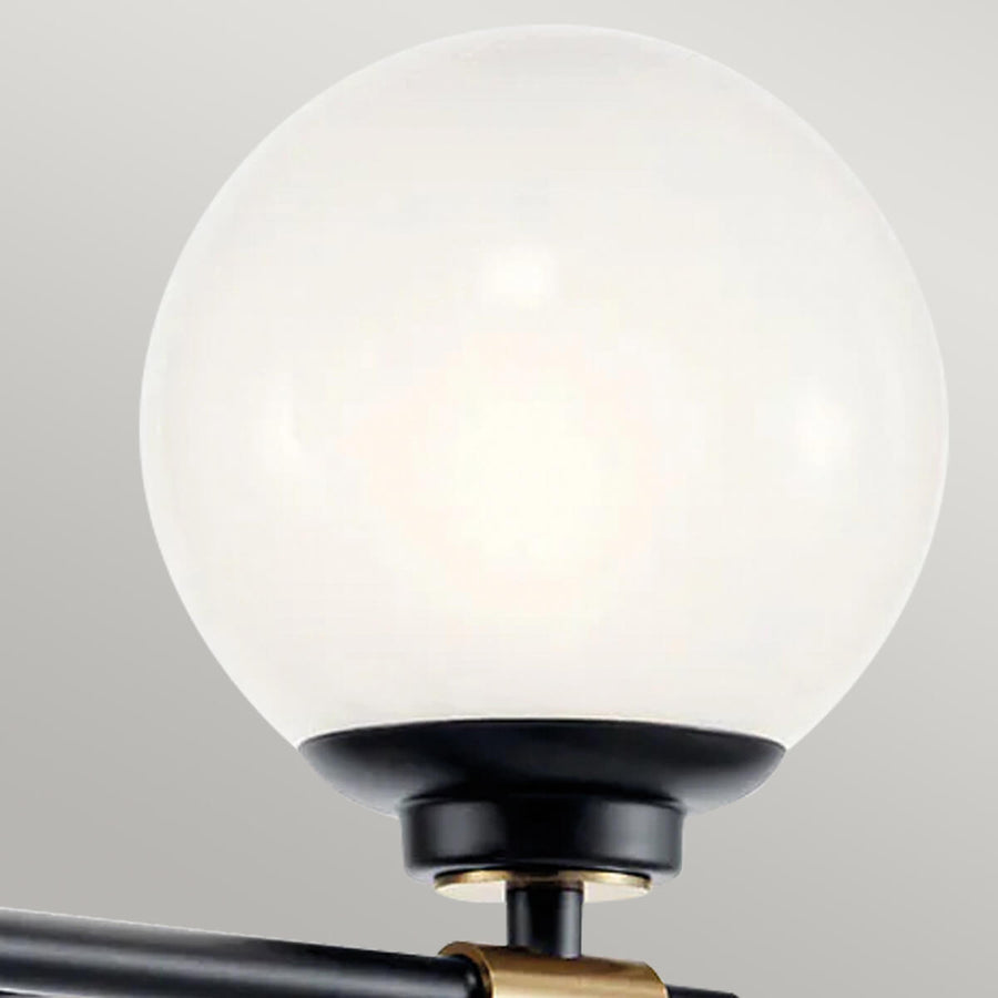 Gros plan sur un globe en verre opalin et sa bague en laiton sur support noir.