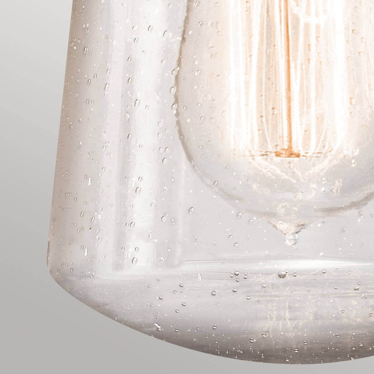 Gros plan du verre moucheté et de l'ampoule allumée vue en transparence.