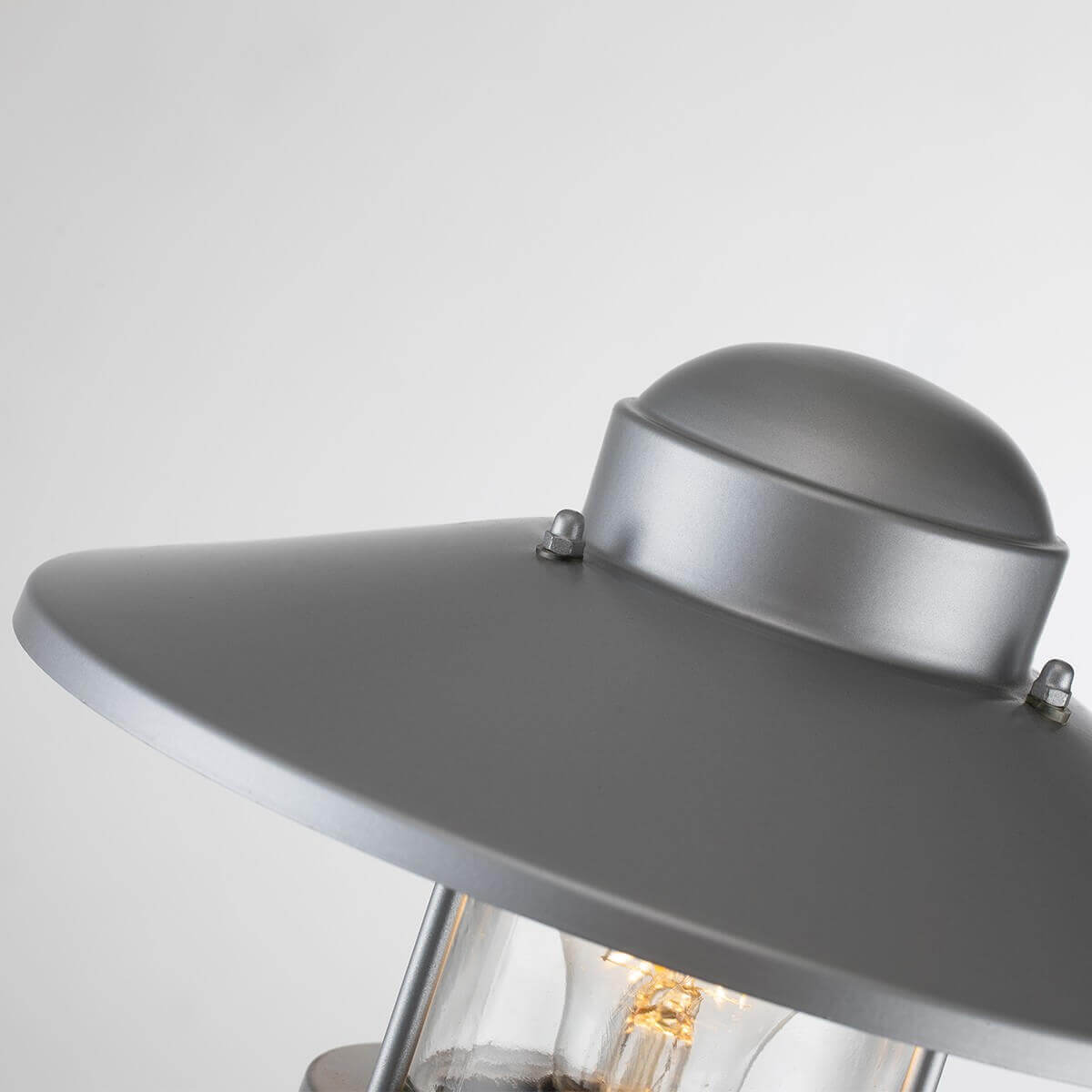 Détail du chapeau métallique argenté avec vis apparentes et finition mate.