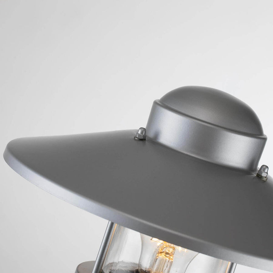 Détail du chapeau métallique argenté avec vis apparentes et finition mate.