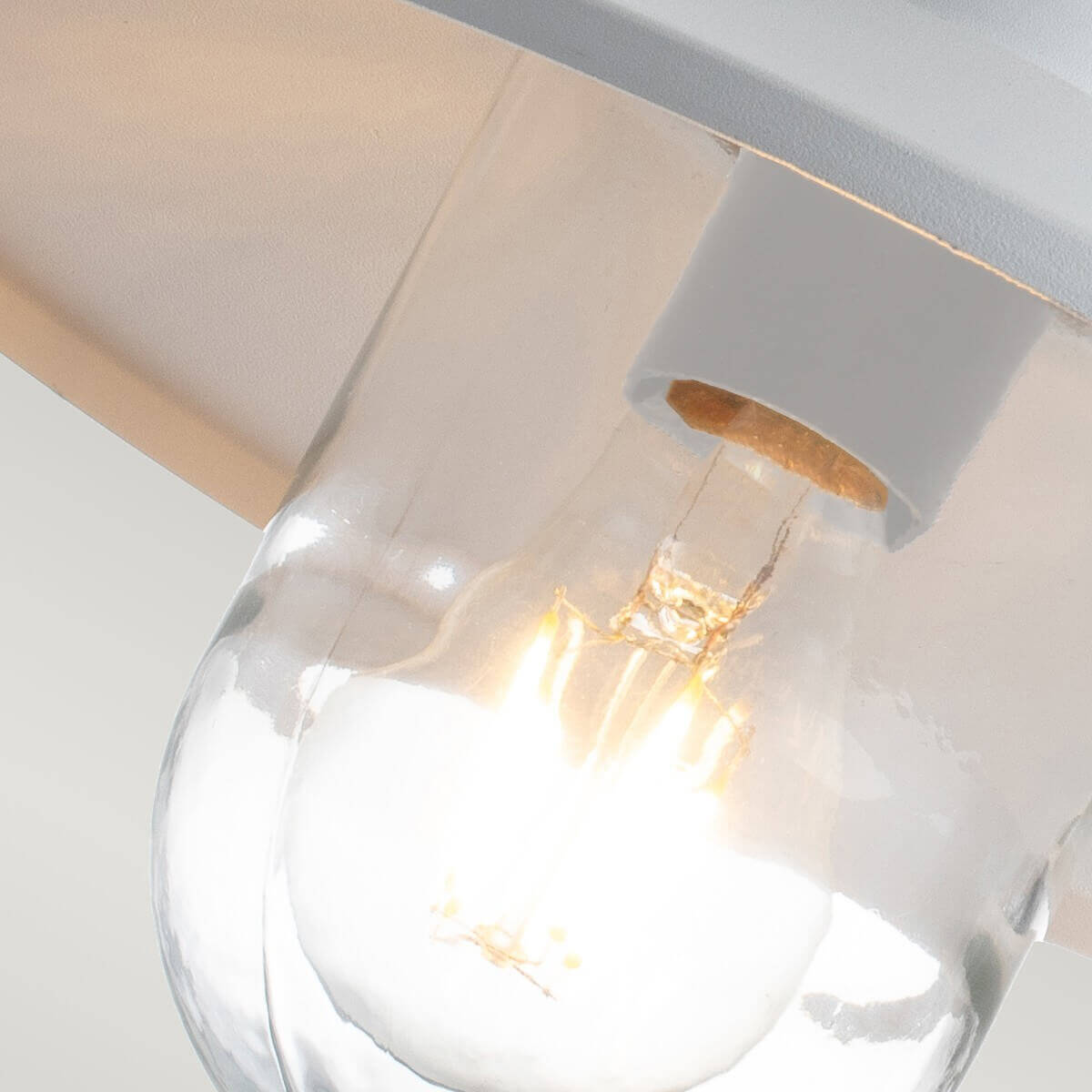 Gros plan sur l'ampoule à filament allumée dans son globe de verre transparent