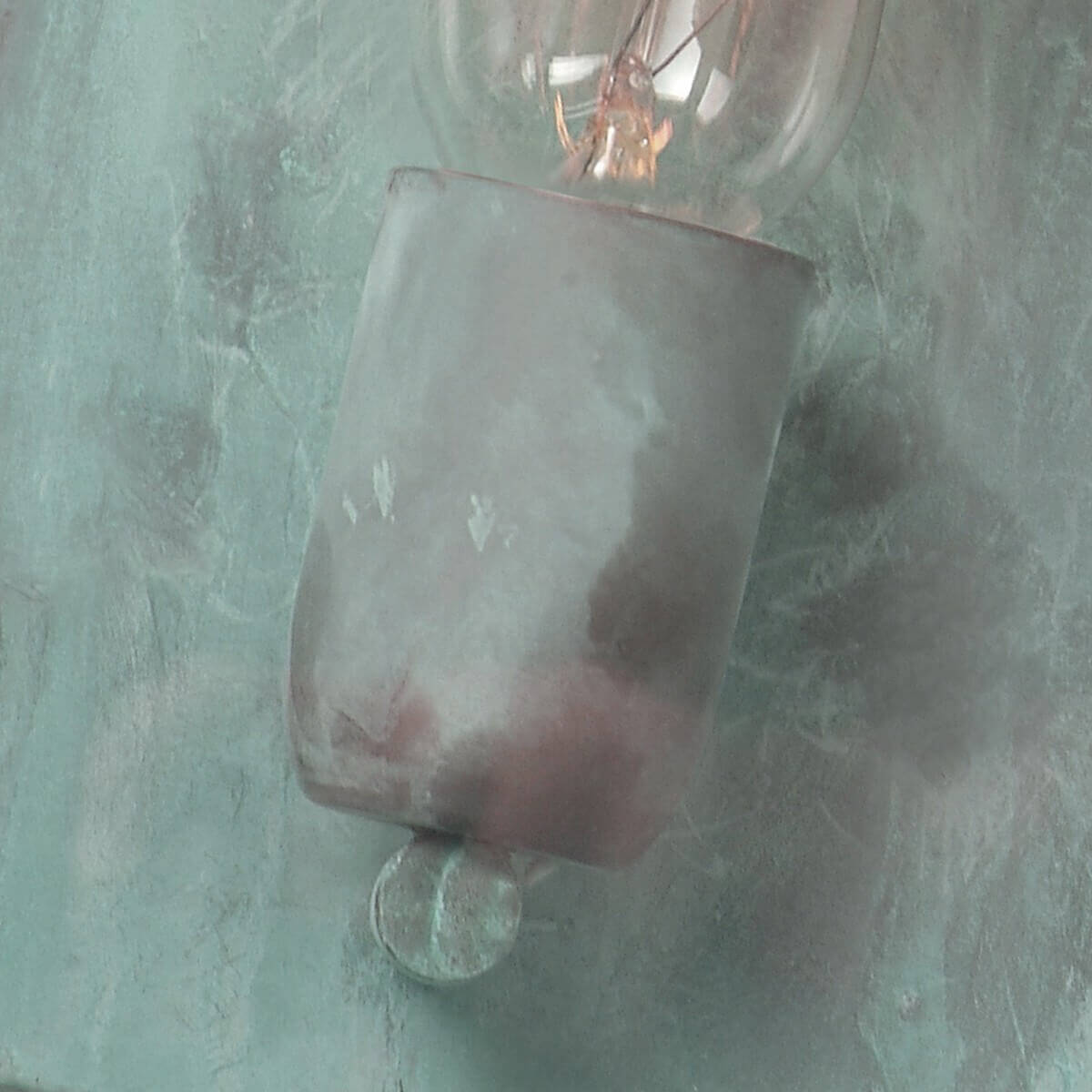 Détail de la douille et de l'ampoule sur fond de tôle verdie