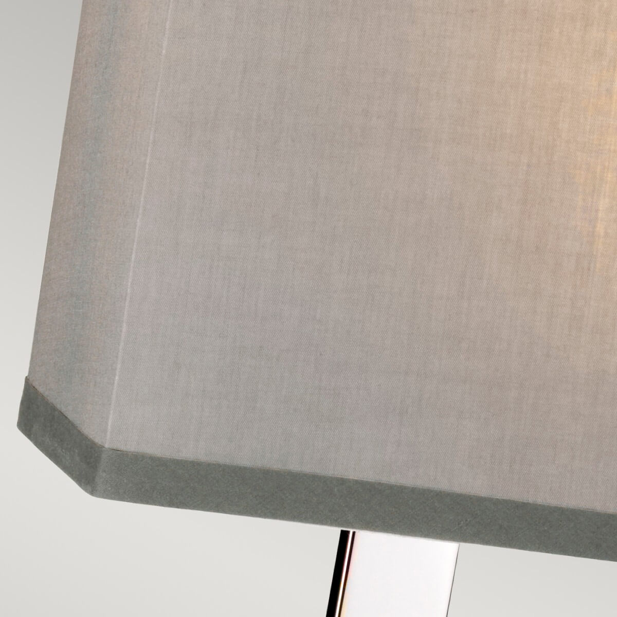 Gros plan sur un coin de l'abat-jour gris clair avec bordure noire et armature visible.